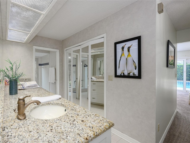 bathroom featuring baseboards, a textured ceiling, and vanity