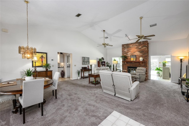 living room with ceiling fan with notable chandelier, a fireplace, visible vents, and high vaulted ceiling