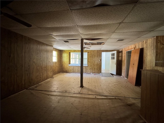 basement with wood walls and a drop ceiling