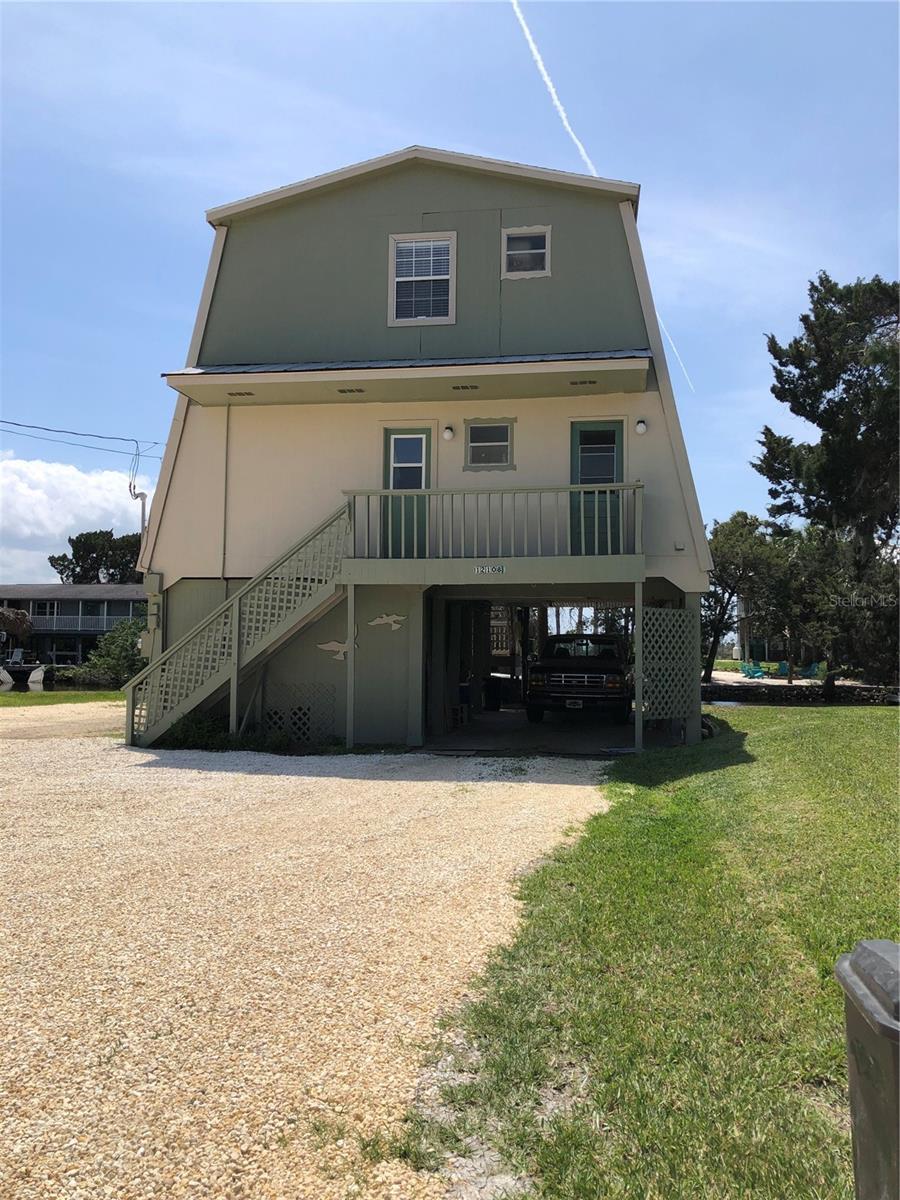 rear view of property with a porch, a yard, driveway, and stairway