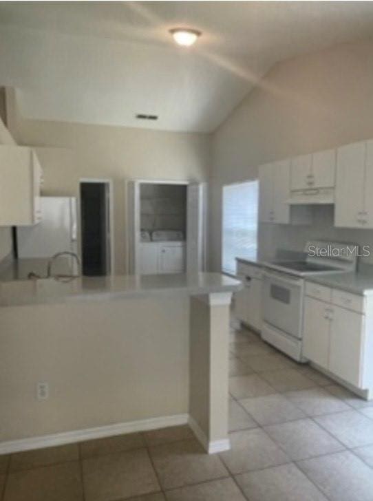 kitchen featuring white appliances, under cabinet range hood, light tile patterned floors, and lofted ceiling