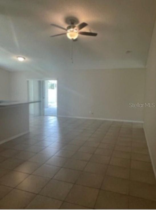 spare room with vaulted ceiling, baseboards, and a ceiling fan