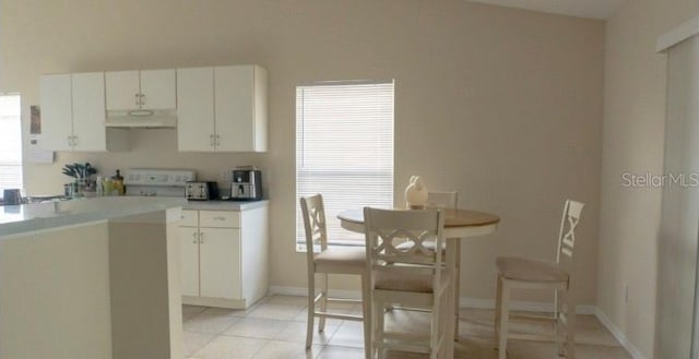 kitchen featuring light countertops, white cabinetry, light tile patterned floors, and extractor fan