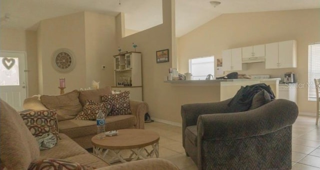 living room featuring baseboards, vaulted ceiling, and light tile patterned floors