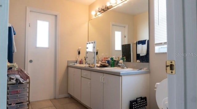 bathroom with double vanity, a sink, tile patterned flooring, and a healthy amount of sunlight