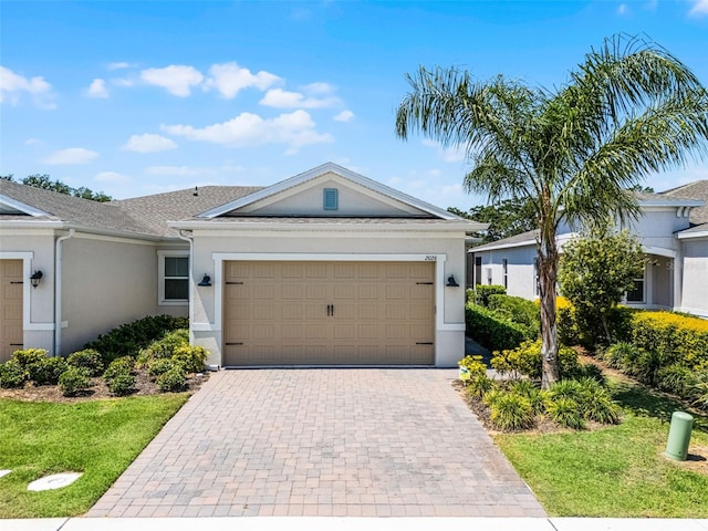 ranch-style house with a garage, a front yard, decorative driveway, and stucco siding