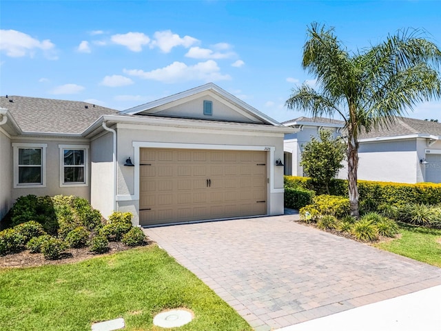 ranch-style home featuring a garage, stucco siding, and decorative driveway