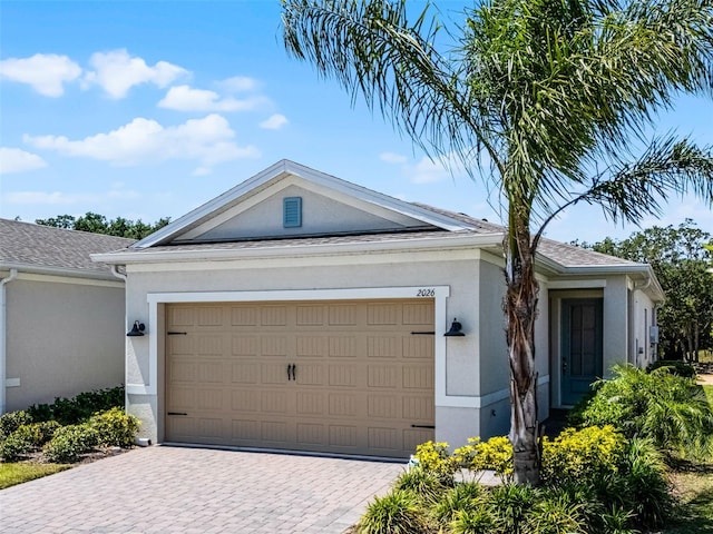 view of front of house with stucco siding, decorative driveway, and a garage