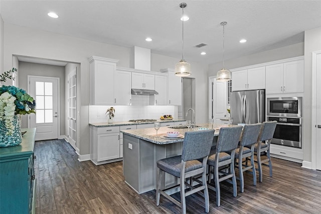 kitchen with stainless steel appliances, under cabinet range hood, white cabinetry, and dark wood-style flooring