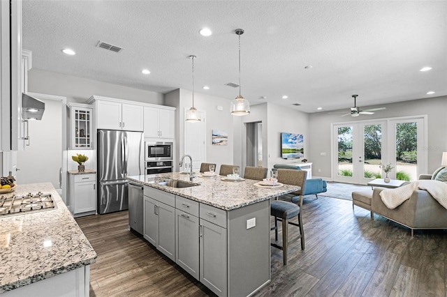 kitchen featuring a sink, open floor plan, ceiling fan, a kitchen bar, and appliances with stainless steel finishes
