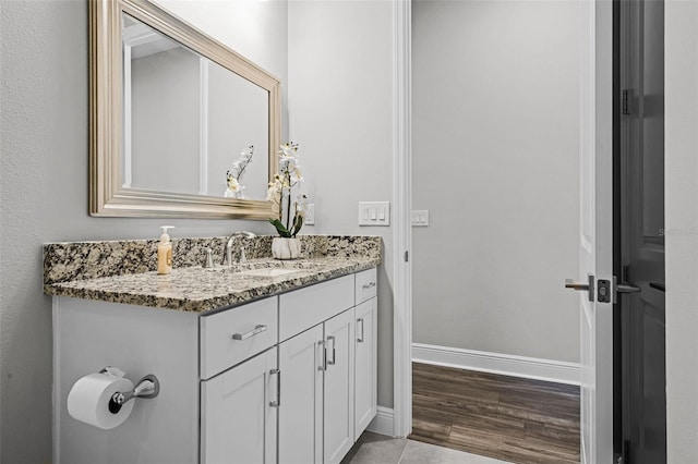 bathroom with wood finished floors, baseboards, and vanity