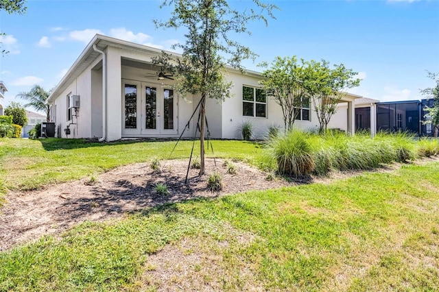 back of house featuring central air condition unit, french doors, a yard, stucco siding, and ceiling fan