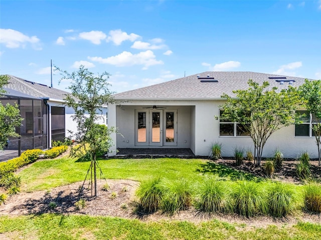rear view of property featuring stucco siding, a yard, a shingled roof, and ceiling fan