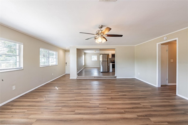 unfurnished living room with ornamental molding, baseboards, a ceiling fan, and wood finished floors