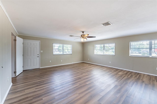 unfurnished room featuring baseboards, visible vents, a wealth of natural light, and dark wood-style flooring