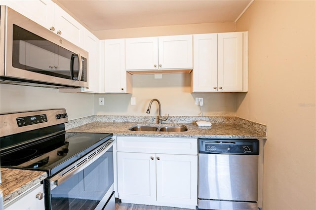 kitchen featuring white cabinets, light stone counters, stainless steel appliances, and a sink