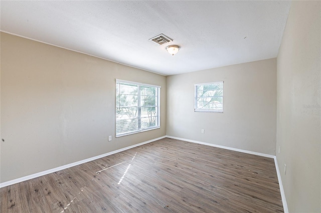 unfurnished room with baseboards, wood finished floors, and visible vents