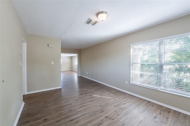 spare room featuring wood finished floors, visible vents, and baseboards