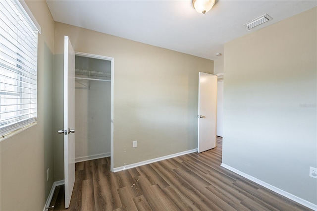unfurnished bedroom featuring visible vents, baseboards, wood finished floors, and a closet