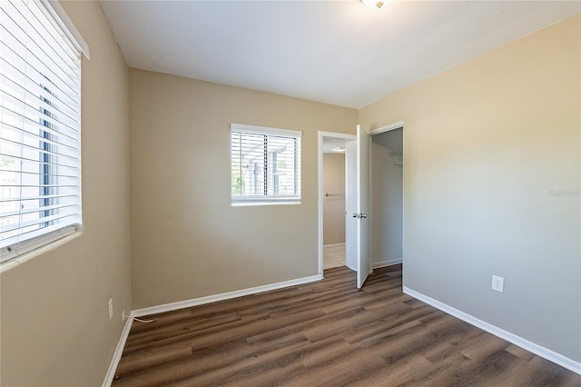unfurnished bedroom with baseboards, dark wood-style floors, and a closet