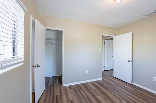 unfurnished bedroom with baseboards, wood finished floors, visible vents, and a closet
