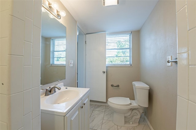 bathroom with marble finish floor, a wealth of natural light, vanity, and toilet