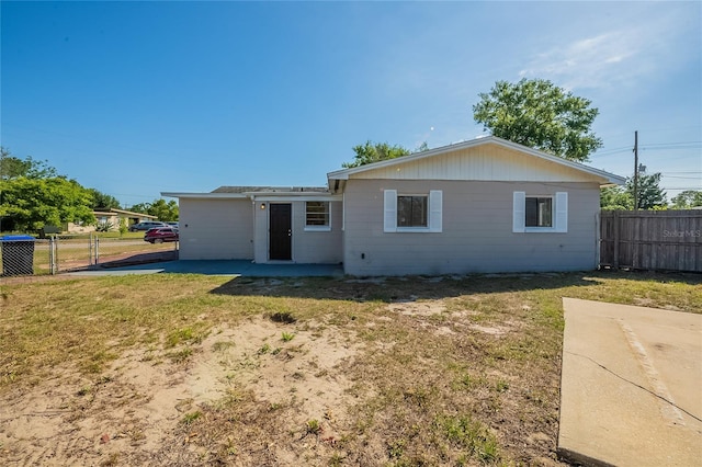 rear view of property with a gate, fence, and a yard