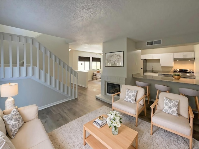 5126 Picadilly Circus Ct Unit 11, Orlando, FL 32839 - living room featuring light wood-style flooring, a glass covered fireplace, visible vents, stairway, and baseboards