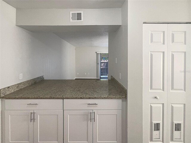 5126 Picadilly Circus Ct Unit 11, Orlando, FL 32839 - kitchen with visible vents, white cabinets, and dark stone counters