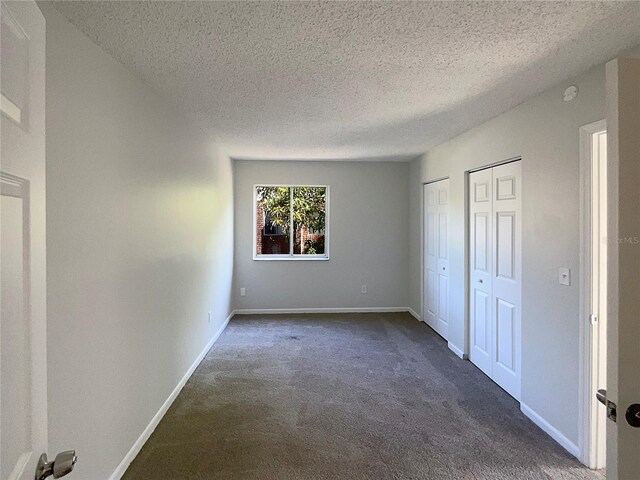 5126 Picadilly Circus Ct Unit 11, Orlando, FL 32839 - unfurnished bedroom featuring dark carpet, multiple closets, and a textured ceiling
