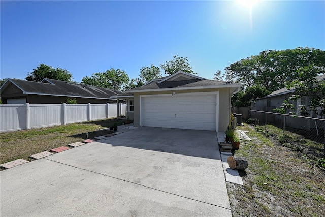 exterior space featuring fence, a garage, driveway, and stucco siding