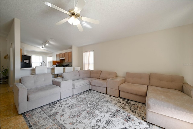 living area featuring a wealth of natural light, ceiling fan, a textured ceiling, and lofted ceiling