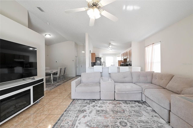living room with light tile patterned flooring, visible vents, a ceiling fan, and vaulted ceiling