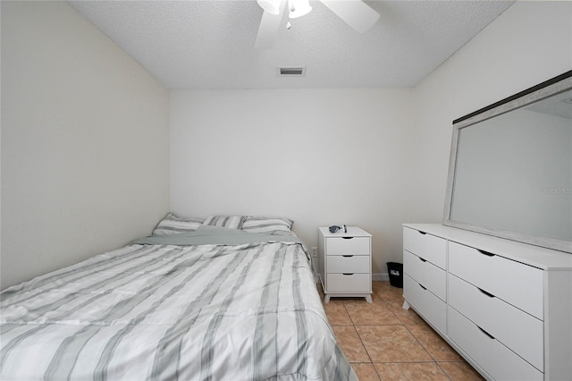 bedroom featuring a textured ceiling, light tile patterned flooring, a ceiling fan, and visible vents