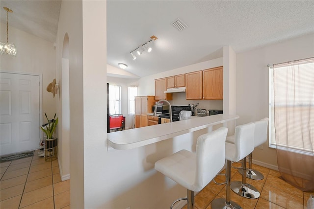 kitchen with visible vents, under cabinet range hood, vaulted ceiling, electric range, and light tile patterned flooring