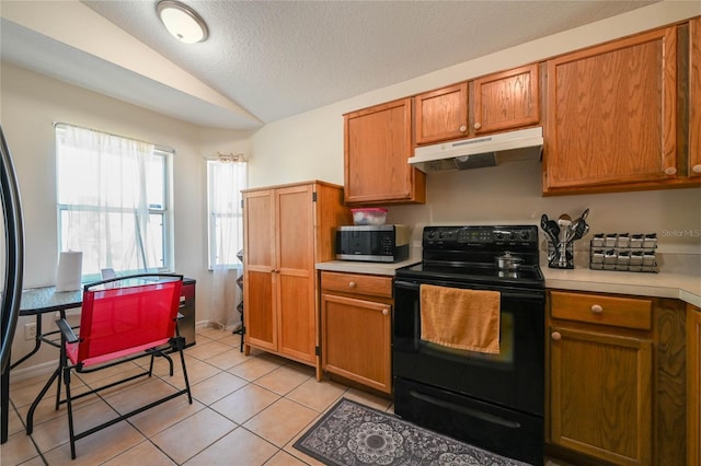 kitchen featuring black range with electric cooktop, light countertops, under cabinet range hood, stainless steel microwave, and lofted ceiling