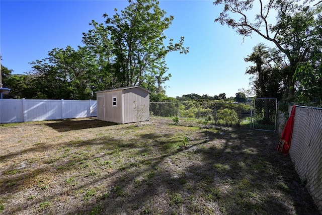 view of yard featuring a shed, a fenced backyard, an outdoor structure, and a gate