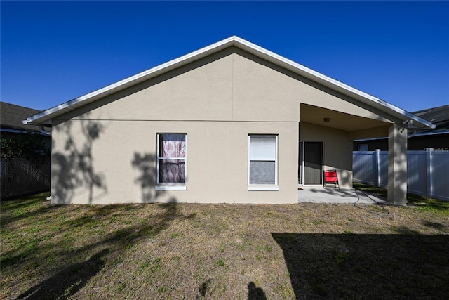 back of property featuring a patio, stucco siding, fence, and a lawn