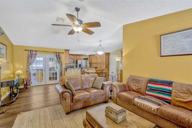 7655 Persian Ct, Orlando, FL 32819 - living area with a textured ceiling, light wood-type flooring, vaulted ceiling, visible vents, and ceiling fan with notable chandelier