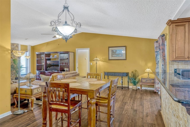 7655 Persian Ct, Orlando, FL 32819 - dining space with dark wood-style floors, vaulted ceiling, a ceiling fan, baseboards, and a textured ceiling