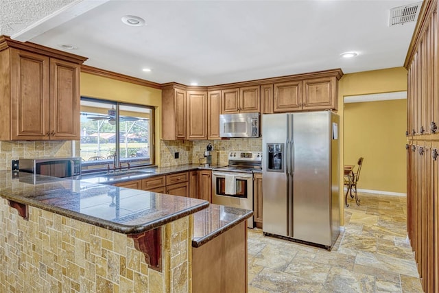 7655 Persian Ct, Orlando, FL 32819 - kitchen featuring brown cabinetry, stone tile flooring, a peninsula, appliances with stainless steel finishes, and visible vents