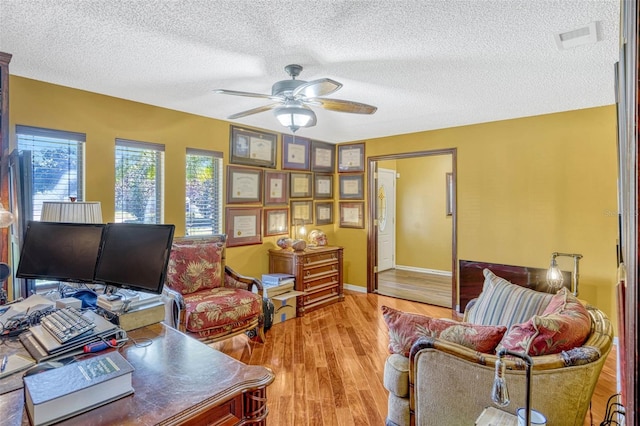 7655 Persian Ct, Orlando, FL 32819 - living area with visible vents, a ceiling fan, baseboards, light wood-style flooring, and a textured ceiling