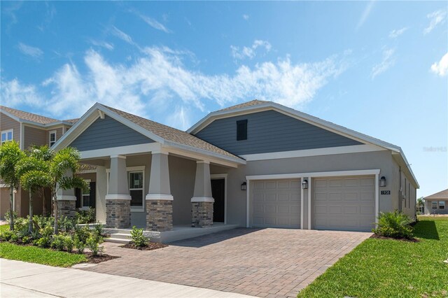 1908 Blissful Dr, Kissimmee, FL 34744 - craftsman house with a porch, stone siding, a garage, stucco siding, and decorative driveway