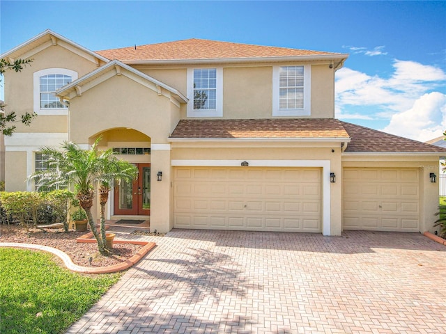 view of front of home featuring stucco siding, french doors, roof with shingles, and decorative driveway