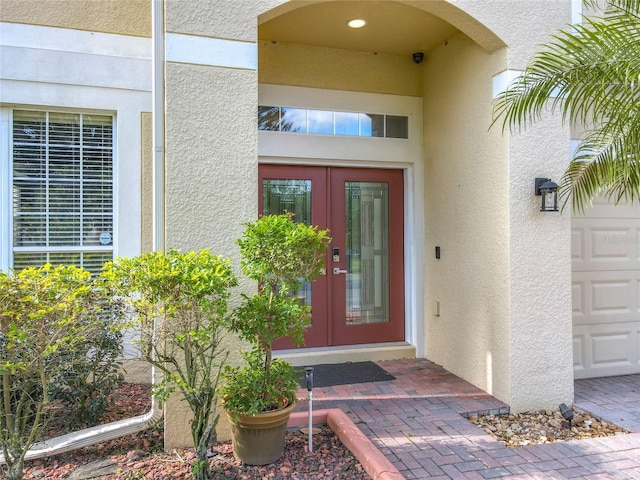 doorway to property featuring stucco siding, a garage, and french doors