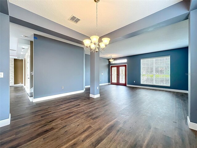 empty room featuring visible vents, baseboards, a notable chandelier, and dark wood-style floors