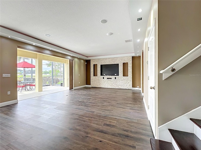 unfurnished living room with visible vents, baseboards, wood finished floors, and a textured ceiling