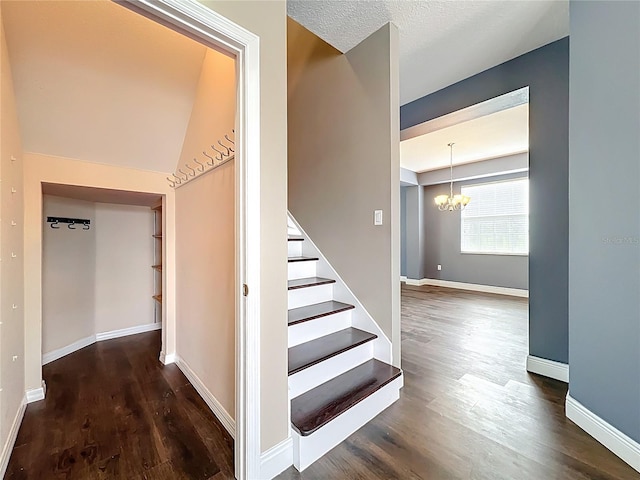 stairs with baseboards, wood finished floors, and an inviting chandelier
