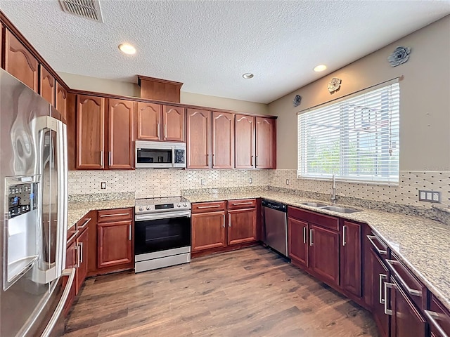 kitchen featuring a sink, tasteful backsplash, visible vents, wood finished floors, and appliances with stainless steel finishes