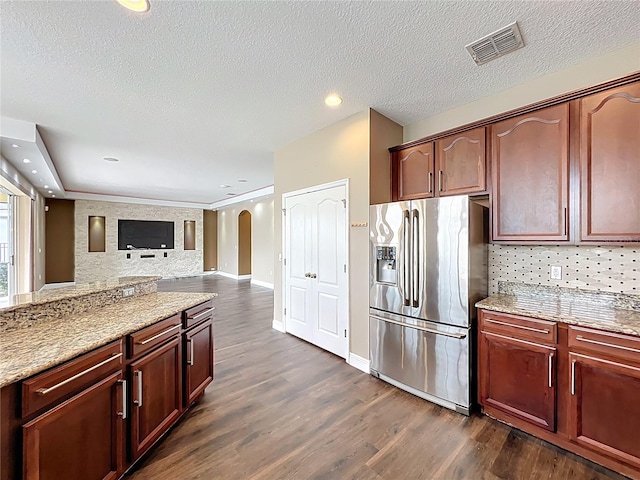 kitchen featuring decorative backsplash, open floor plan, stainless steel fridge, arched walkways, and visible vents